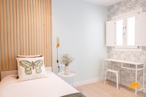 A bedroom with a bed, a bedside table with a lamp, a small stool, and a white desk with a chair. - Apartamento Villalobos 5 by C diz Time Apartments (Cádiz)