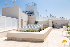 A rooftop terrace with a glass enclosure, seating area, and potted plants. - Apartamento Villalobos 5 by C diz Time Apartments (Cádiz)