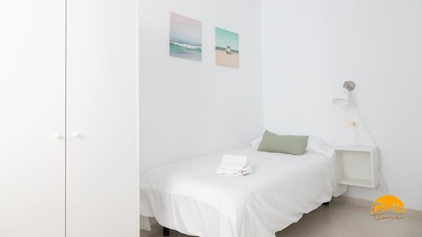 A minimalist bedroom with a bed, a nightstand, and two wall-mounted pictures. - Green Home by Cadiz Time (Cádiz)