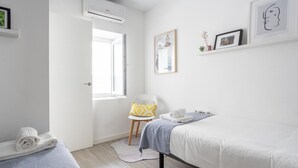 A modern hotel room with a bed, a chair, a small table, and an air conditioning unit. - Atico Catedral by Cadiz Time (Cádiz)