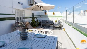 A rooftop terrace with a dining table set for two, outdoor seating, and potted plants. - Atico Catedral by Cadiz Time (Cádiz)