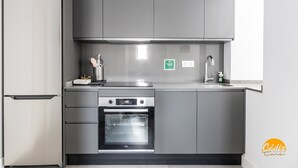 A modern kitchen with a stainless steel refrigerator, oven, and built-in microwave. There is a sink with a faucet and a soap dispenser on the countertop. - La Casa del Alfarero by Cadiz Time (Cádiz)