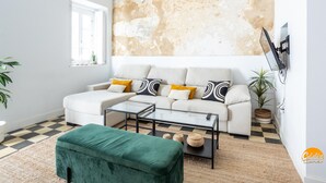 A living room with a white sofa, a glass coffee table, and a green ottoman. - La Casa del Alfarero by Cadiz Time (Cádiz)