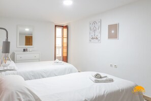 Ein Hotelzimmer mit zwei Einzelbetten, einem Nachttisch mit Lampe, einem Spiegel, einer kleinen Kommode und zwei Wandbildern.