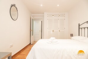 A bedroom with a bed, a bedside table, a mirror, a wardrobe, and a door leading to another room. - Villa Lola by Cadiz Time (Cádiz)