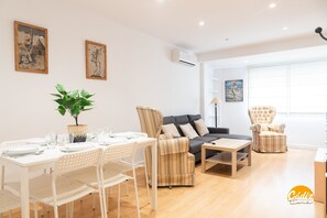 A modern living room with a dining area, featuring a sofa, armchairs, a coffee table, and a dining table set for four. - Villa Lola by Cadiz Time (Cádiz)