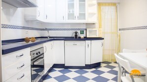 Una cucina compatta con mobili bianchi, un forno a microonde, un forno e una lavastoviglie.