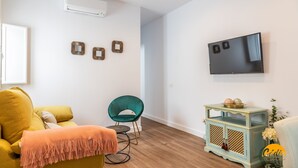 A modern living room with a yellow sofa, teal armchair, and a small side table with decorative items. - El Patio del Mar by Cadiz Time (Cádiz)