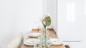 A dining table set with plates, glasses, and a vase with flowers. - El Patio del Mar by Cadiz Time (Cádiz)