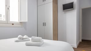 A bedroom with a bed, white curtains, a TV, and a wardrobe. - El Patio del Mar by Cadiz Time (Cádiz)