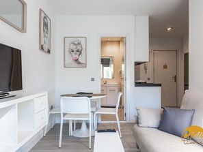 A modern living room with a sofa, a dining table with chairs, a TV, and artwork on the walls. - Apartamento Plaza Mina by Cadiz Time (Cádiz)