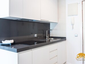 A modern kitchen with a black countertop, stainless steel sink, and white cabinets. - Apartamento Plaza Mina by Cadiz Time (Cádiz)