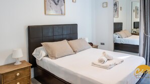 A hotel room with a large bed, a nightstand, a lamp, and a mirror. - Apartamento Plaza Mina by Cadiz Time (Cádiz)