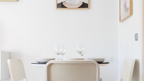 A dining area with a white table set for two, two chairs, and two wine glasses. - Apartamento Plaza Mina by Cadiz Time (Cádiz)