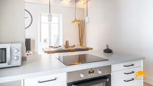 Una cocina moderna con horno integrado, microondas y comedor con mesa y sillas de madera.