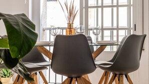 En matplats med ett bord dukat för två personer, en vas med torkade vassstjälkar och en utsikt genom stora fönster.