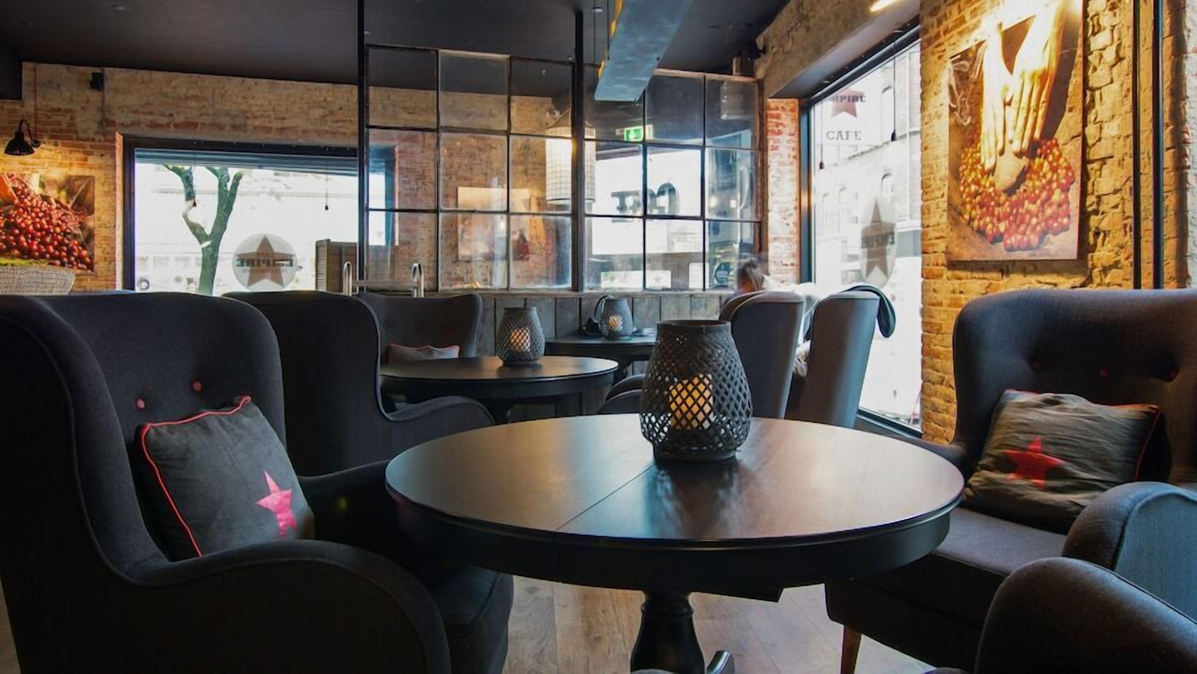 A cozy cafe interior with brick walls, round tables, and comfortable seating.