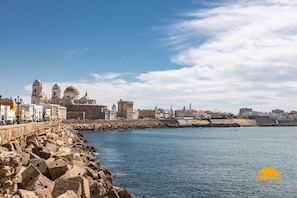 A coastal cityscape with historic buildings, a stone seawall, and calm waters. - Blue Home by Cadiz Time (Cádiz)