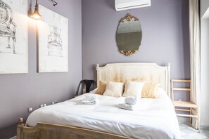 A neatly made bed with white linens and a wooden headboard, a wall-mounted mirror, and two framed sketches of chairs. - Blue Home by Cadiz Time (Cádiz)