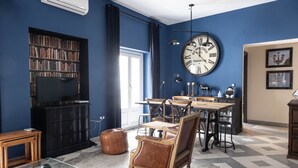 Ein Zimmer mit einem großen Bücherregal, einem runden Tisch und einem Ledersessel.