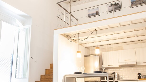 A modern kitchen with white cabinets, a stainless steel refrigerator, and hanging pendant lights. - Casa Isabela by Cadiz Time (Cádiz)