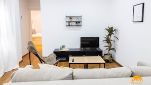 Een moderne woonkamer met een bank, een eettafel, een televisie en een plant.