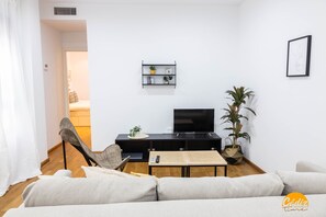 A modern living room with a sofa, a dining table, a TV, and a plant. - Rincon del Mar Free Parking by Cadiz Time (Cádiz)