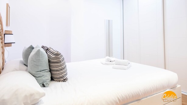Een hotelkamer met een bed, kussens, een handdoek en een kledingkast.