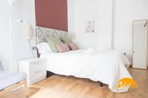 A modern bedroom with a white bed, a nightstand, a lamp, and a chair. - Apartamento Caleta Free Parking by Cadiz Time (Cádiz)