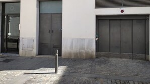 Ein Gebäude mit zwei großen grauen Türen, einem kleinen Fenster und einem Lüftungsgitter an der oberen Wand.