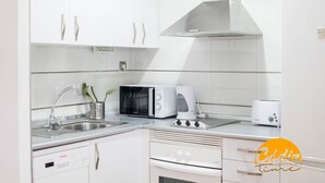 Eine moderne Küche mit weißen Schränken, einer Edelstahl-Spüle, einer Mikrowelle, einem Toaster und einem eingebauten Backofen.