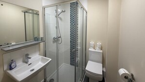 Ein Badezimmer mit Duschkabine, Waschbecken und Toilette.