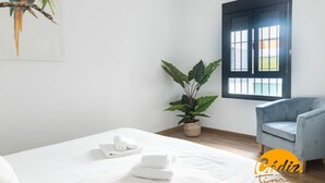 A hotel room with a bed, a chair, a window, and a potted plant. - Corazon del Mar Free Parking by Cadiz Time (Cádiz)