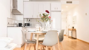 A modern kitchen with white cabinets, a microwave, and a dining area with a table set for two. - Corazon del Mar Free Parking by Cadiz Time (Cádiz)