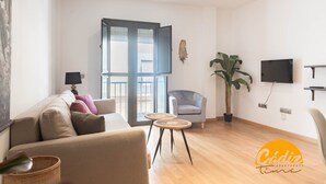 A modern living room with a sofa, a chair, a television, and a large window. - Corazon del Mar Free Parking by Cadiz Time (Cádiz)