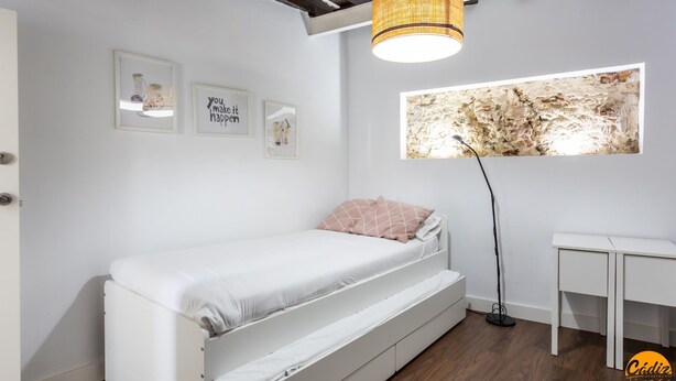 A bedroom with a bed, a small desk, a wall-mounted artwork, and a ceiling light fixture. - Diana de Columela by Cadiz Time (Cádiz)
