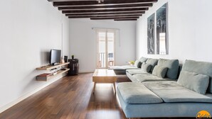 A modern living room with a wooden floor, a grey sofa, a television, and a coffee machine. - Diana de Columela by Cadiz Time (Cádiz)