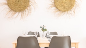 A dining table with four chairs, a vase with flowers, and two woven wall decorations. - Casa Capuchinos Free Parking by Cadiz Time (Cádiz)