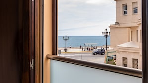 A view from a window overlooking a coastal area with buildings, a street, and a body of water. - Casa Capuchinos Free Parking by Cadiz Time (Cádiz)