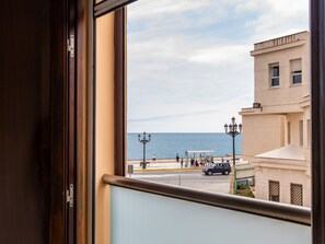 Vista desde una ventana sobre una zona costera con edificios, una calle y una masa de agua.