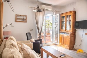 A living room with a sofa, a table, a TV, and a wooden cabinet. - La Bella Escondida by Cadiz Time (Cádiz)
