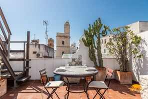 A rooftop terrace with a round table set for two, surrounded by chairs, a large cactus, and potted plants. - La Bella Escondida by Cadiz Time (Cádiz)