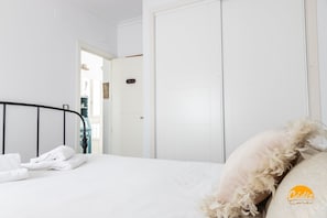 A bedroom with a neatly made bed, white walls, and a closed door. - La Bella Escondida by Cadiz Time (Cádiz)
