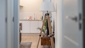 Eine moderne Küche mit weißen Schränken, Holzboden und einer Stehlampe.