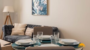 A dining area with a table set for four, including plates, glasses, and cutlery. A laptop is on the table, and a lamp is on a tripod stand to the left. - Tailor s Home by Cadiz Time (Cádiz)