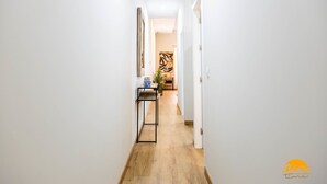 A narrow hallway with a wooden floor, white walls, and a black metal shelf with a blue object on it. - Tailor s Home by Cadiz Time (Cádiz)