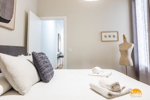 Quarto de hotel com uma cama, um manequim e um quadro na parede.