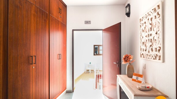 A hallway with wooden cabinets, a white door, a small table with a vase, and a decorative wall panel. - Casa Rehala Nisa by Cadiz Time (Cádiz)