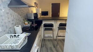 Kompakti keittiö, jossa on mikroaaltouuni, leivänpaahdin ja pesuallas. Siellä on myös kaksi baarijakkaraa ja pieni jääkaappi.