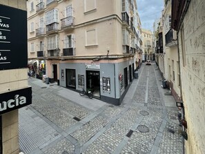 A narrow cobblestone street with buildings on either side, a bicycle parked in front of a wine shop, and a sign for 'Despacho de Vinos'. - Apartamento Las Flores by Cadiz Time (Cádiz)